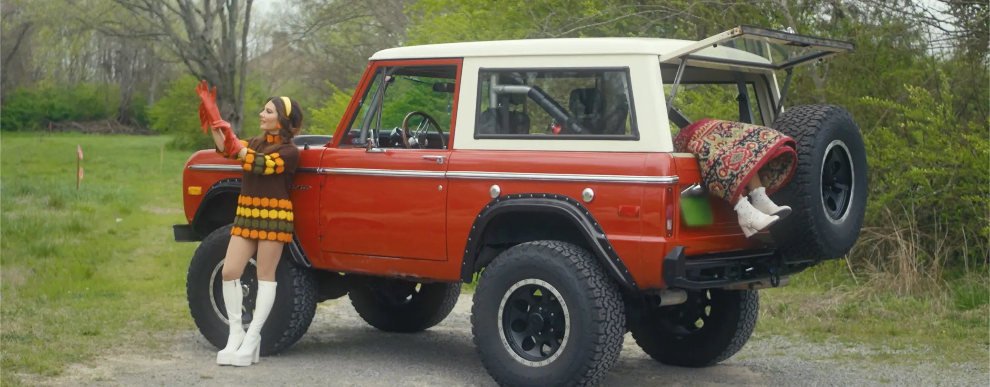 Still from the Good Mourning music video: Dani Rose pulling on red gloves beside a red vintage Bronco